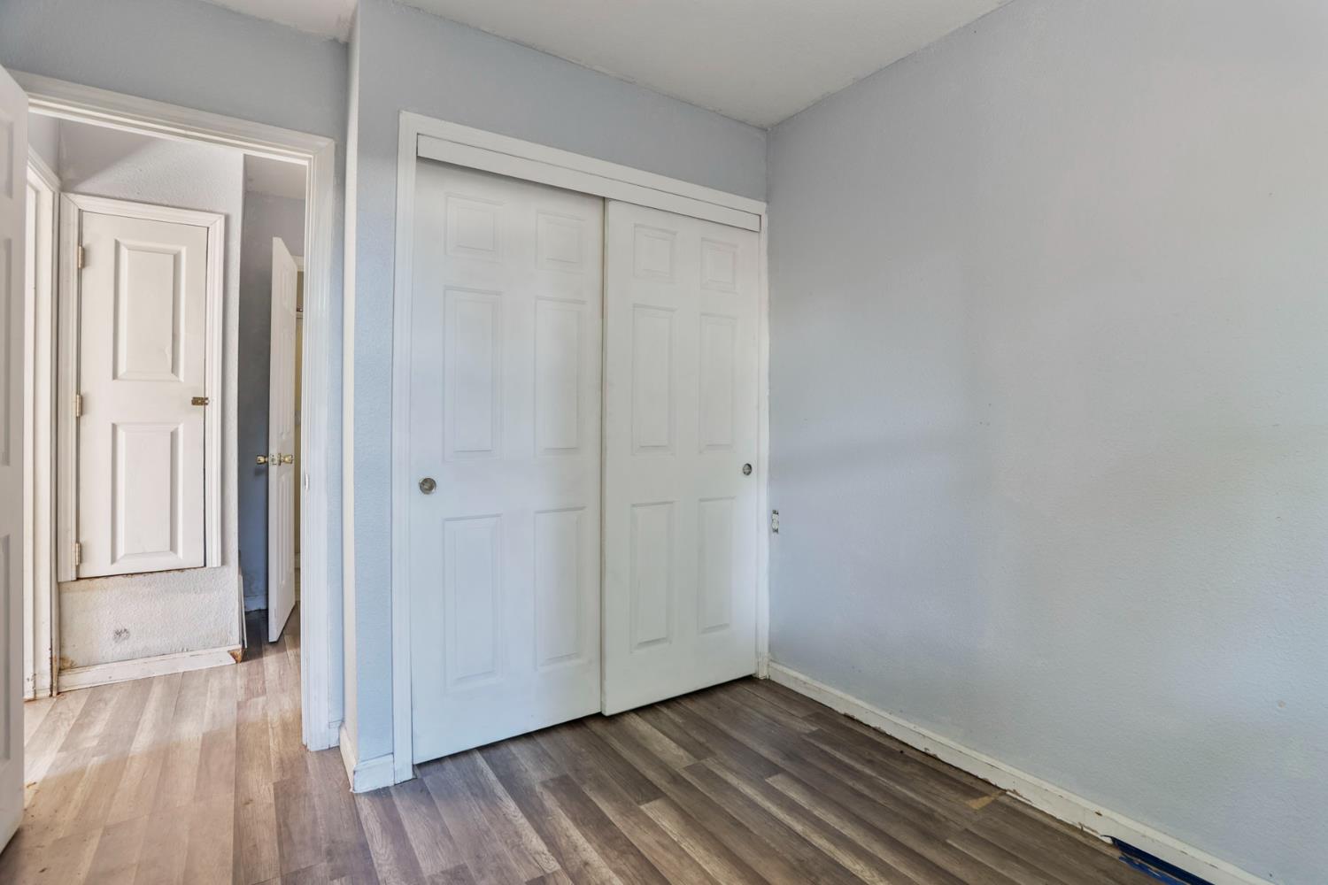916 Elm Avenue Modesto, CA 95351 - Photo 45 of 52 Rear dwelling bedroom area with wood-look flooring, neutral walls, and access to bathroom.