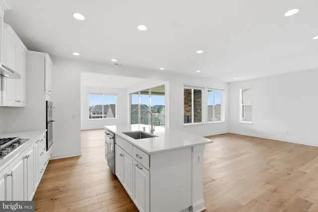 a large white kitchen with kitchen island a large counter top and a stove