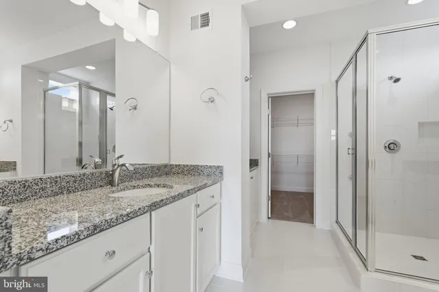 a bathroom with a granite countertop sink mirror and shower