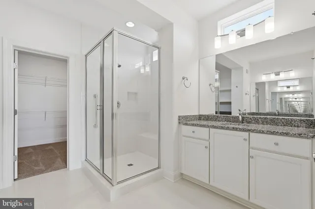 a bathroom with a granite countertop shower sink and mirror