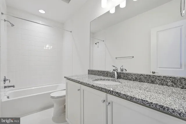 a bathroom with a granite countertop sink a toilet and bathtub
