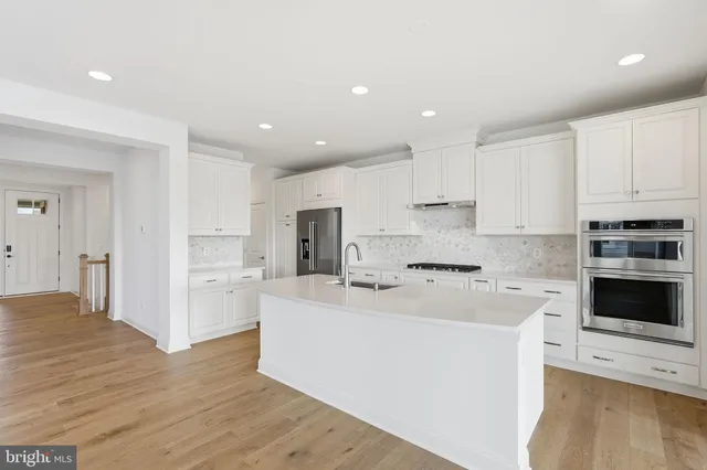 a kitchen with kitchen island a white counter top space cabinets and stainless steel appliances