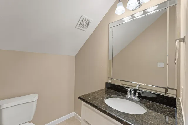 a bathroom with a granite countertop sink a toilet and a mirror