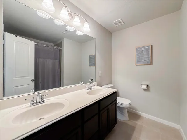 a bathroom with a double vanity sink toilet and a mirror