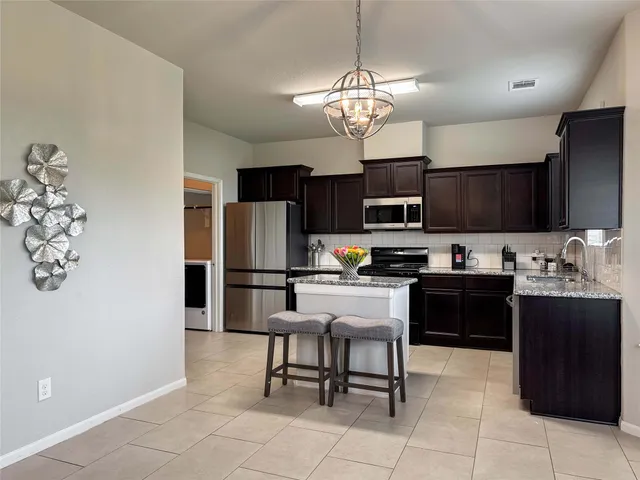 a kitchen with stainless steel appliances granite countertop a refrigerator and a stove top oven