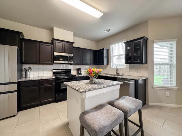 a kitchen with stainless steel appliances granite countertop a stove a sink dishwasher a refrigerator a microwave oven with granite countertops and cabinets