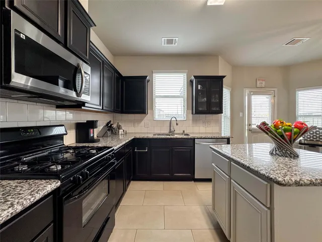 a kitchen with stainless steel appliances granite countertop a sink stove and microwave
