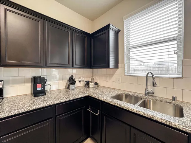 a kitchen with granite countertop a sink a window and cabinets