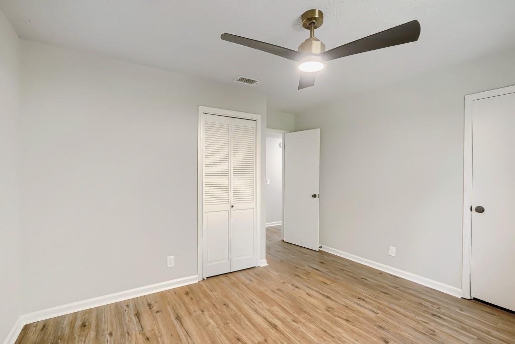 2021 Irwin Bridge Road Northwest Conyers, GA 30012 - Photo 35 of 43 an empty room with wooden floor chandelier fan and windows