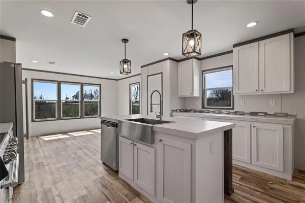a kitchen with kitchen island granite countertop a sink a counter space appliances and cabinets