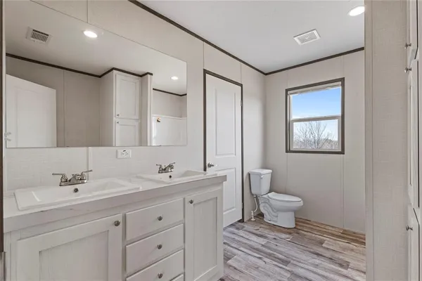 a bathroom with a toilet sink double vanity and mirror