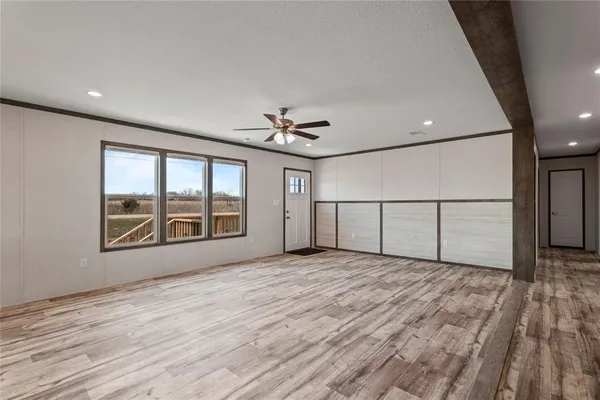 a view of an empty room with a window and wooden floor