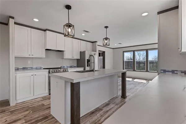 a kitchen with kitchen island a stove a sink a center island and wooden floor