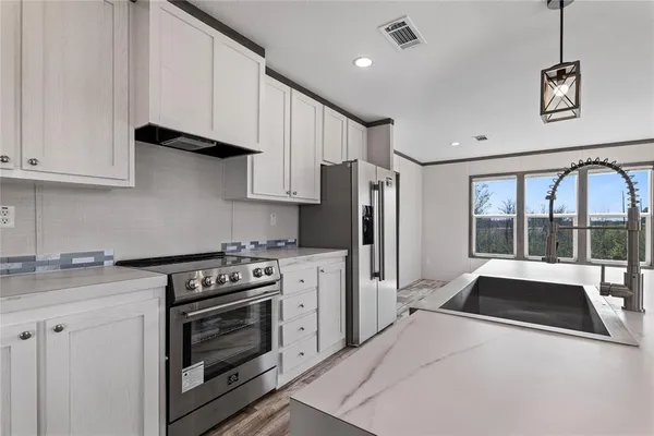 a kitchen with stainless steel appliances a stove a sink and a refrigerator