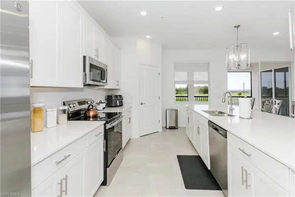 a kitchen with stainless steel appliances a sink a stove top oven a refrigerator a sink and dishwasher with white cabinets