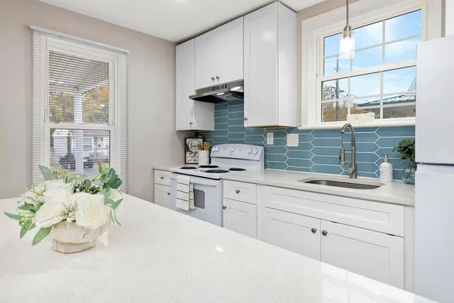 a kitchen with stainless steel appliances kitchen island granite countertop a sink a stove and a window