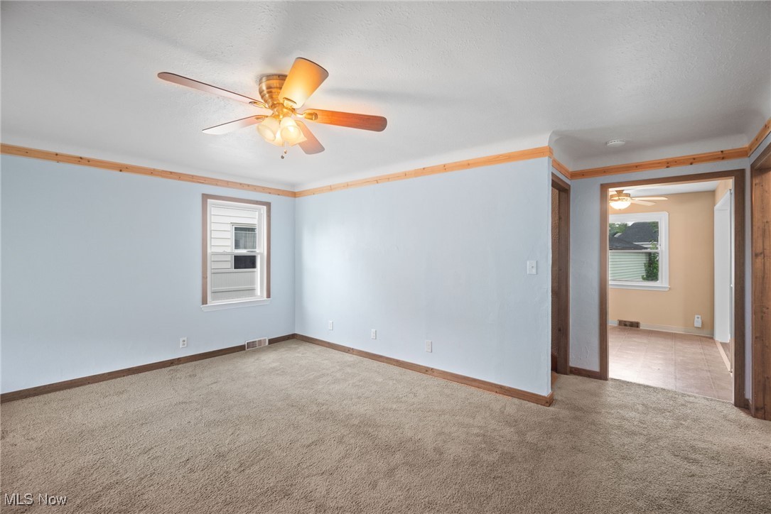 Carpeted spare room featuring crown molding and ceiling fan
