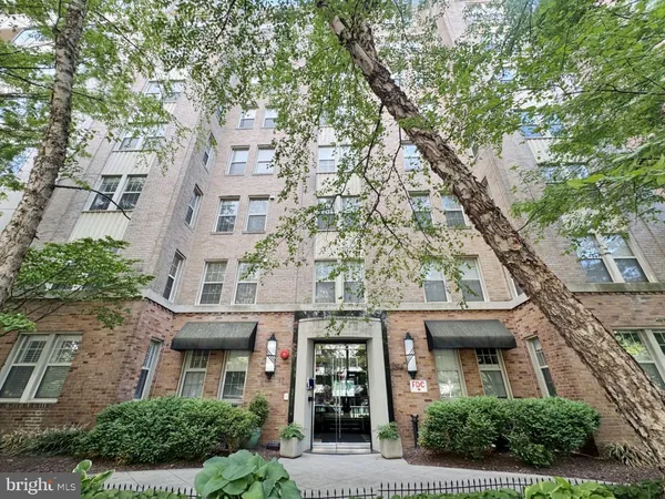an aerial view of a brick house next to a large tree