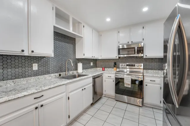 a kitchen with stainless steel appliances granite countertop a sink stove and refrigerator