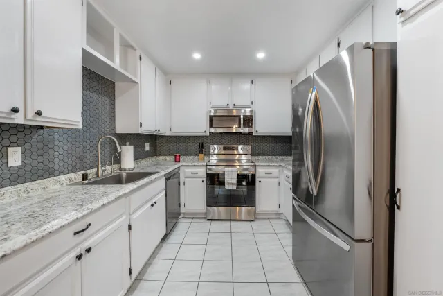 a kitchen with stainless steel appliances granite countertop a refrigerator sink and stove