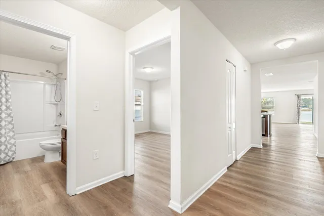 a view of a hallway with wooden floor and a bathroom