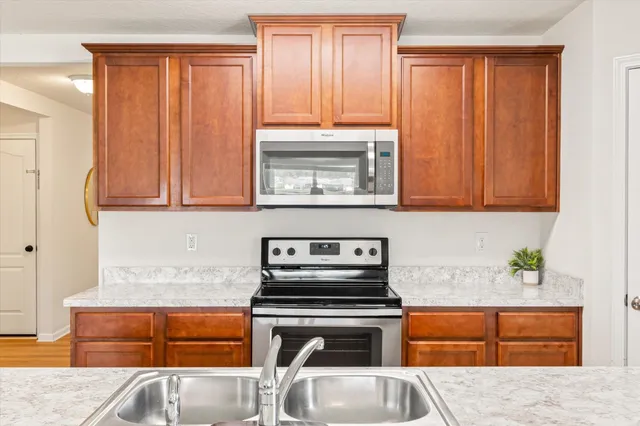 a kitchen with stainless steel appliances granite countertop a stove a sink and a microwave