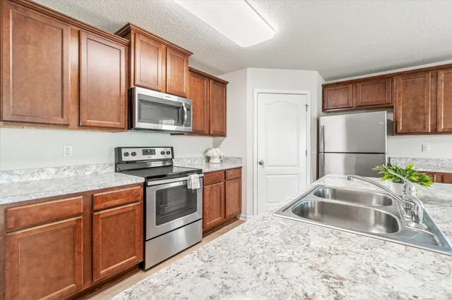 a kitchen with stainless steel appliances granite countertop a sink a stove a refrigerator a microwave oven with cabinets and wooden floor