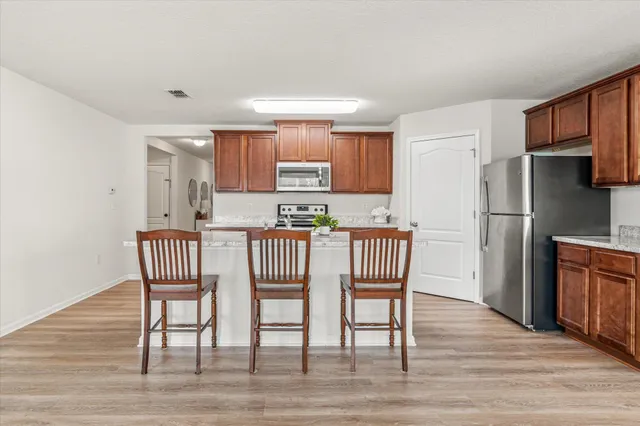 a kitchen with stainless steel appliances granite countertop a dining table chairs refrigerator and a sink