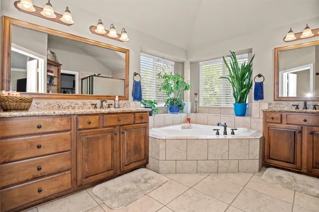 a bathroom with a granite countertop double vanity sink a mirror and a bathtub