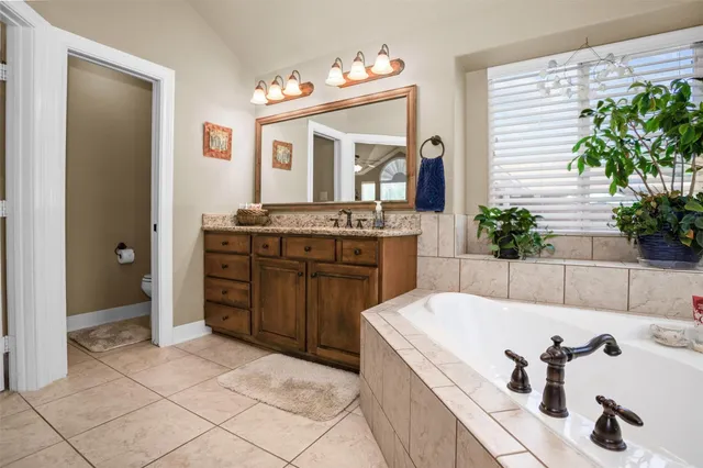 a spacious bathroom with a tub sink and mirror