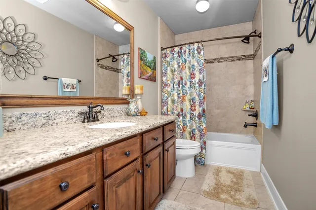 a bathroom with a granite countertop sink a toilet and shower