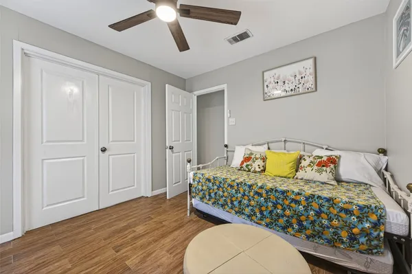 a bedroom with a bed dresser and wooden floor