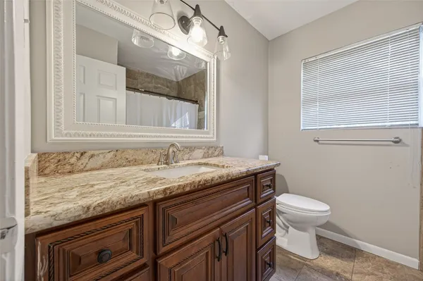 a bathroom with a granite countertop sink a toilet and a mirror