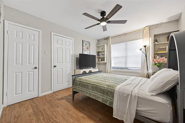 a bedroom with a bed a flat screen tv and a window