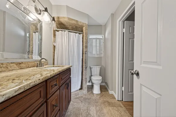 a bathroom with a granite countertop sink toilet and shower