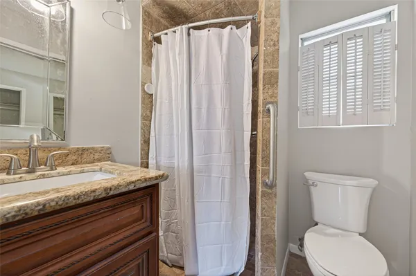 a bathroom with a granite countertop sink toilet and shower