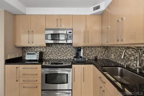 a kitchen with granite countertop white cabinets and stainless steel appliances