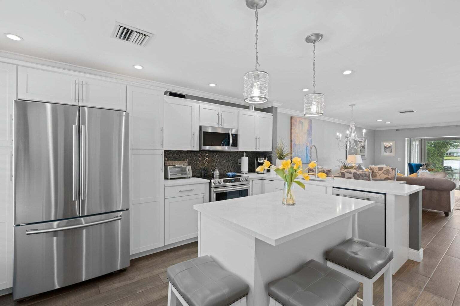 5400 Poppy Place, Unit B Delray Beach, FL 33484 - Photo 1 of 23 a kitchen with refrigerator and chairs