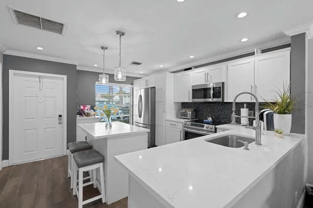 a kitchen with sink a refrigerator and chairs
