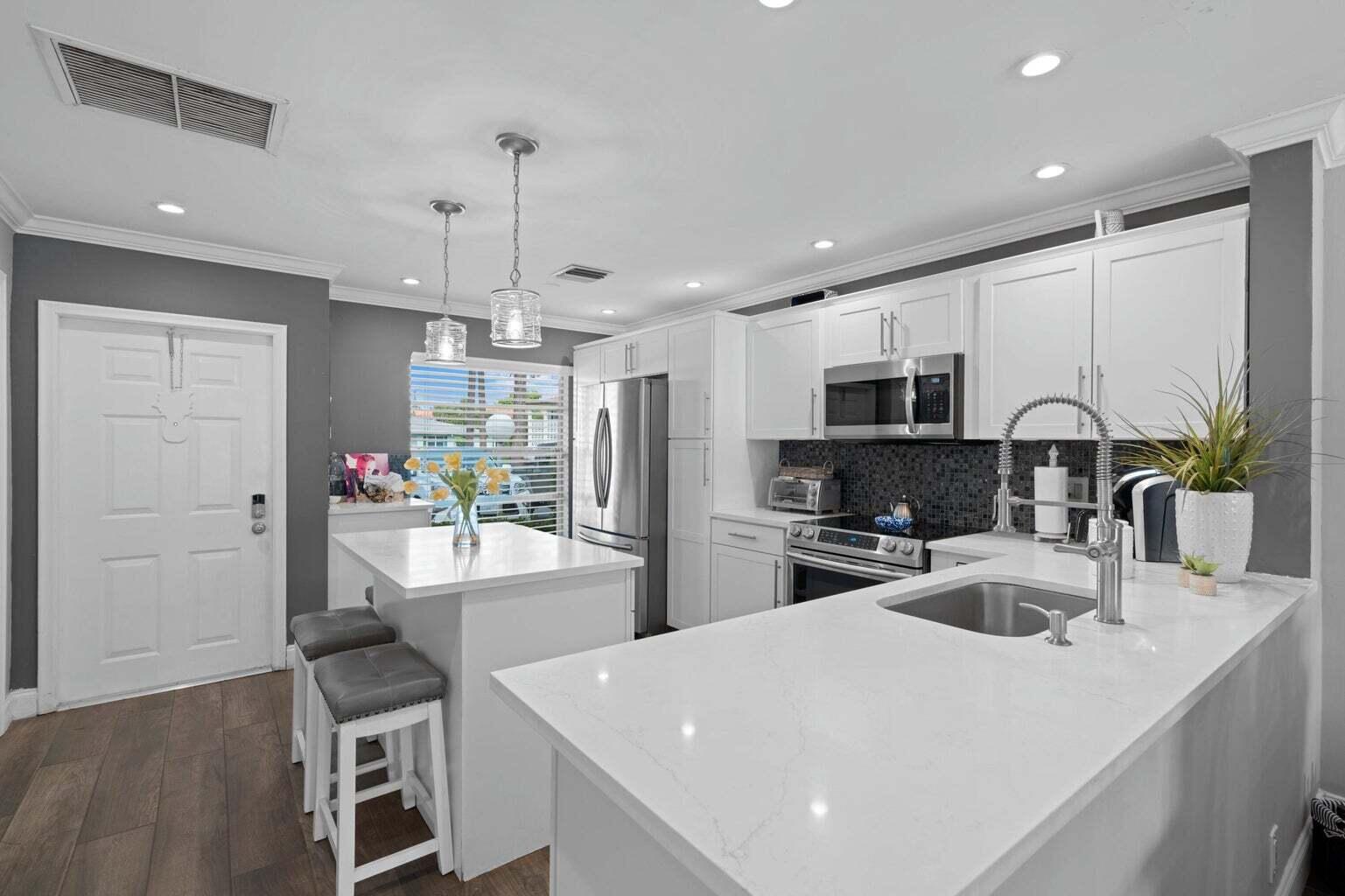 5400 Poppy Place, Unit B Delray Beach, FL 33484 - Photo 2 of 23 a kitchen with sink a refrigerator and chairs