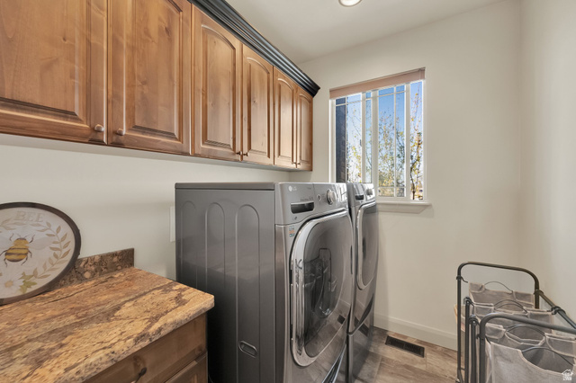 302 Old Farm Road Tooele, UT 84074 - Photo 11 of 30 Laundry room featuring wood cabinetry with crown molding, a built-in countertop with stone finish, and wood-finish flooring