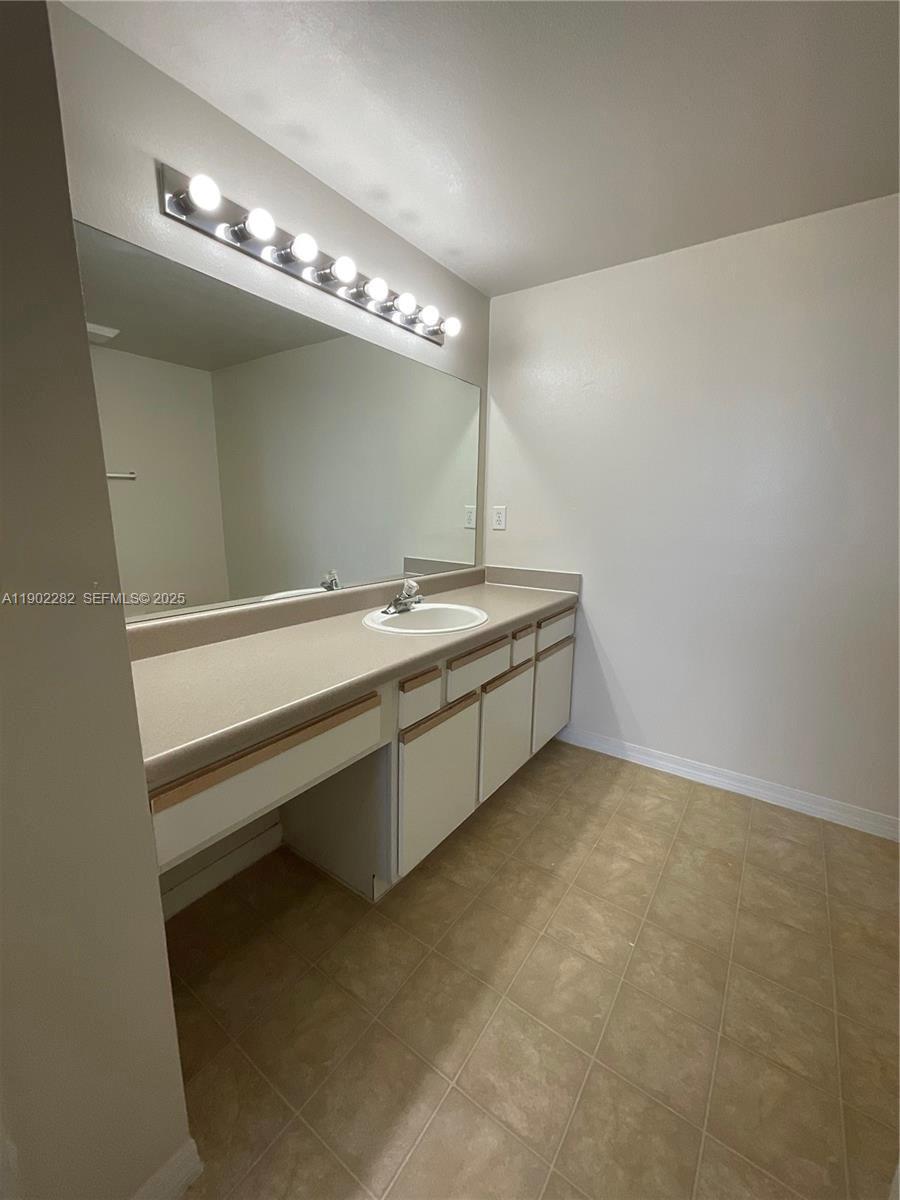 11730 Southwest 2nd Street, Unit 12202 Pembroke Pines, FL 33025 - Photo 14 of 18 a spacious bathroom with a sink a large mirror and a chandelier