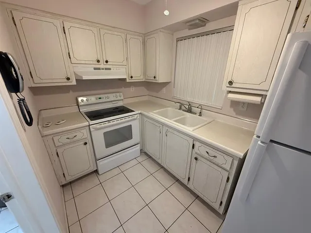 a kitchen with white cabinets sink and stove