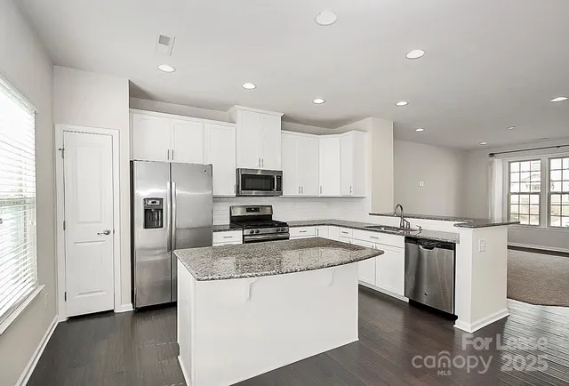 a kitchen with kitchen island granite countertop a stove a sink a refrigerator a counter space and cabinets