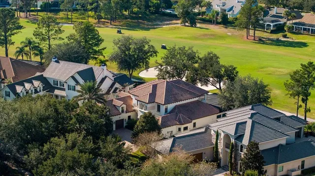 an aerial view of a house with swimming pool and large trees