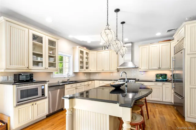 a kitchen with stainless steel appliances a sink a stove a microwave a center island and cabinets