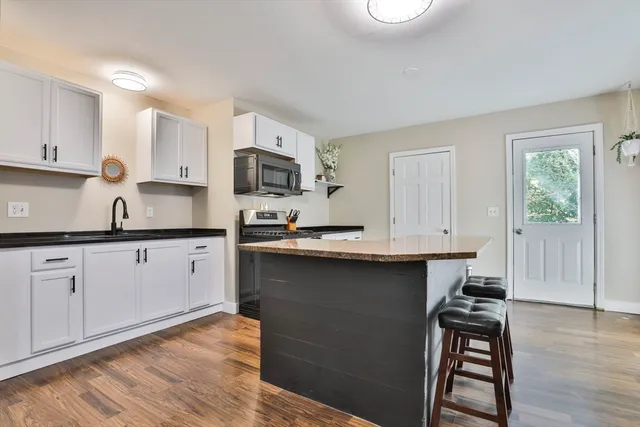 a kitchen with stainless steel appliances a sink dishwasher a stove a microwave a sink and cabinets