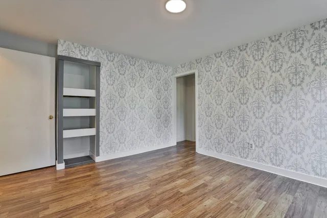a view of an empty room with wooden floor and closet