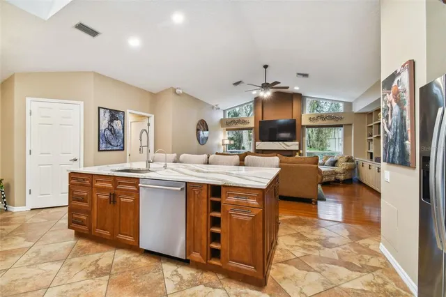 a kitchen with stainless steel appliances granite countertop a sink a stove a dining table and chairs with wooden floor