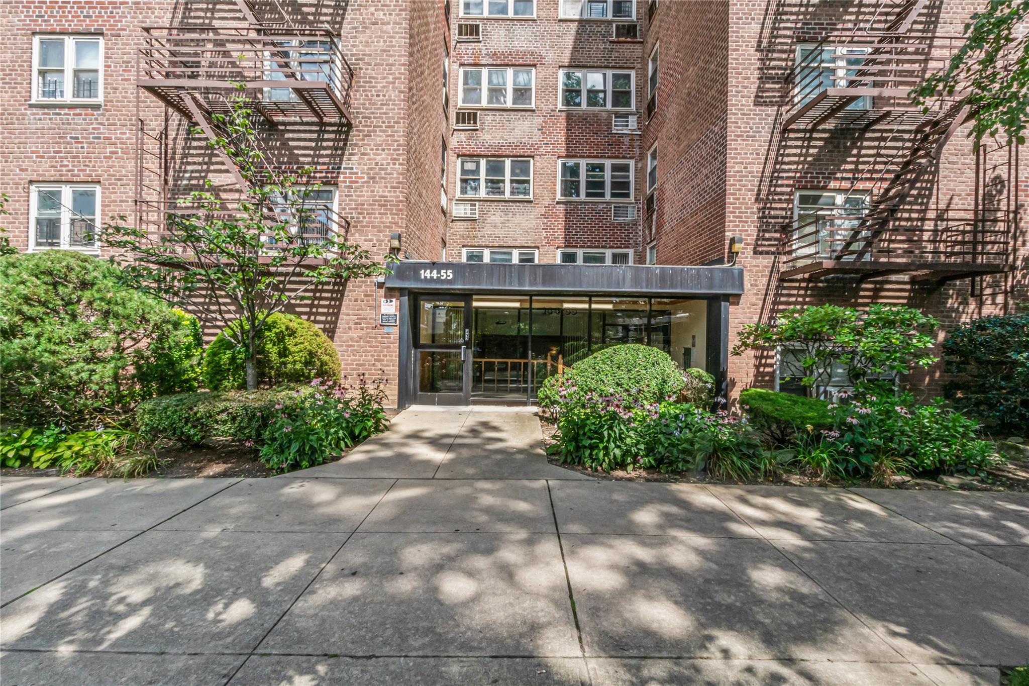 144-55 Melbourne Avenue, Unit 2E Queens, NY 11367 - Photo 1 of 21 a front view of a building with garden and parking